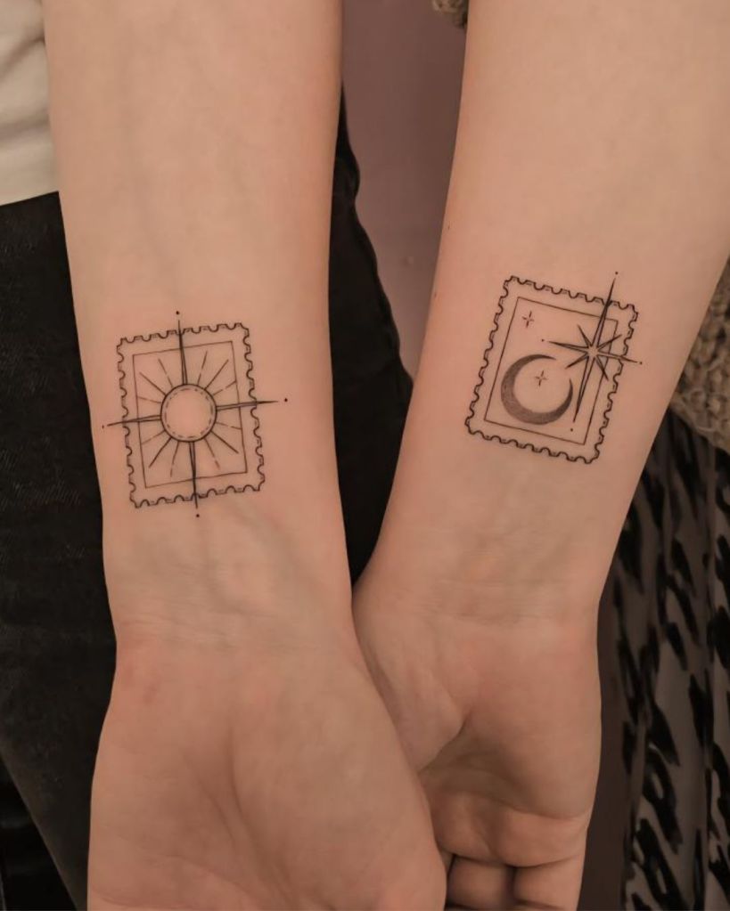A close-up of two arms displaying matching fine-line tattoos of a sun and a moon inside stamp-like outlines.