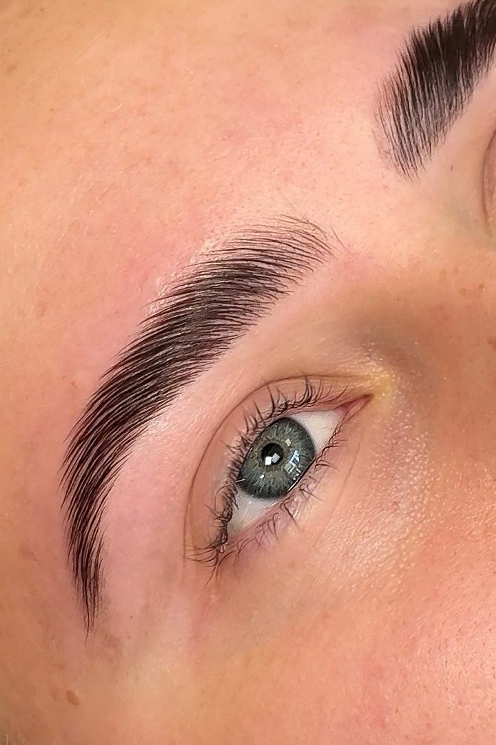 Close-up of a person's eye and well-groomed eyebrow, showcasing detailed hair texture and natural skin tone.