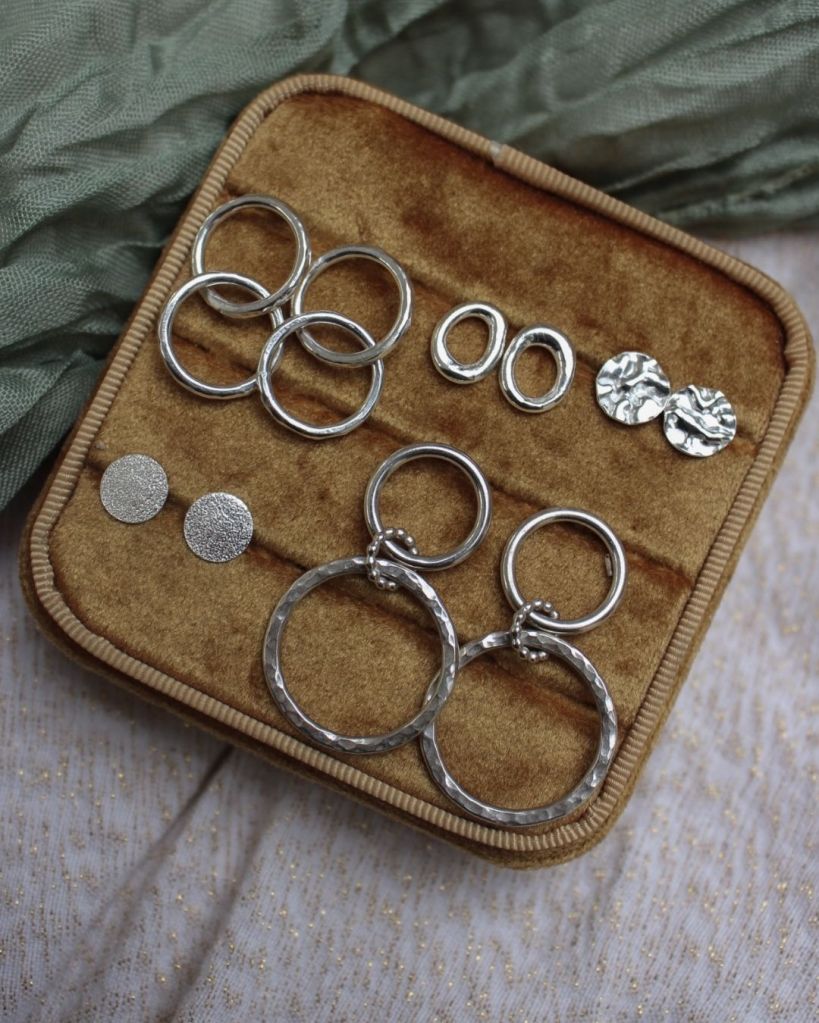 Collection of silver earrings displayed in a velvety jewelry box.