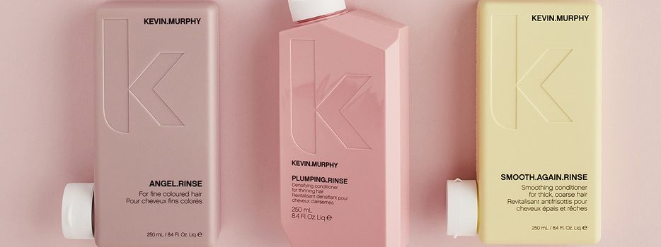 Three bottles of KEVIN.MURPHY hair care products displayed together on a pastel background. The bottles are labeled ANGEL.RINSE, PLUMPING.RINSE, and SMOOTH.AGAIN.RINSE, each designed for different hair types.